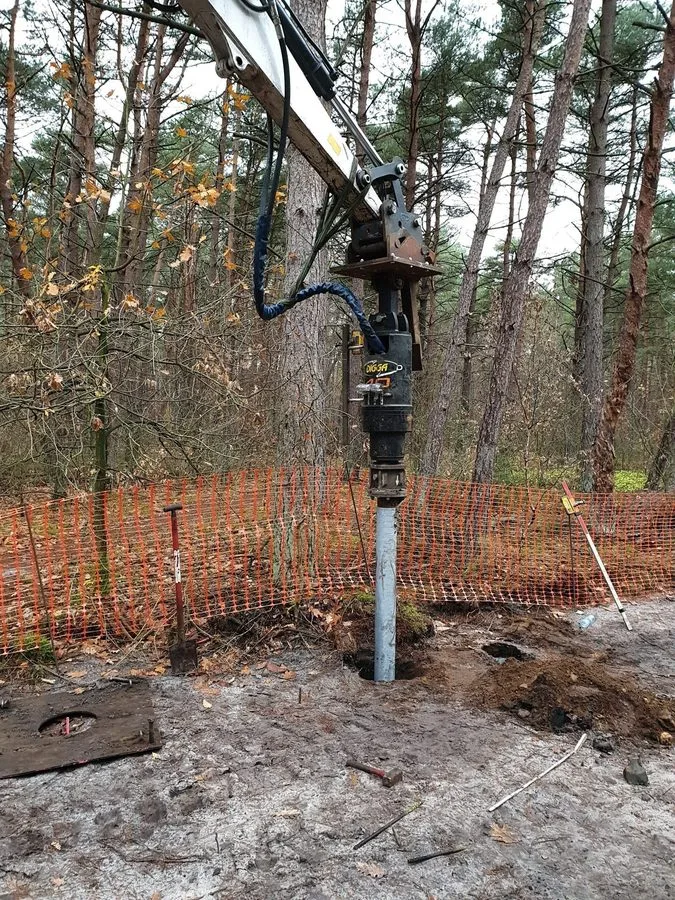 Kaivinkone asentamassa kuumasinkitty&auml; ruuvipaalua m&auml;ntymets&auml;&auml;n Boslandissa, Belgiassa