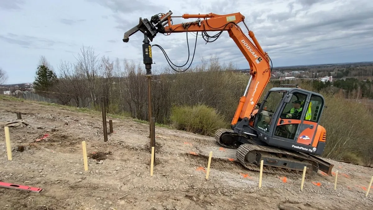 Excavator installing screw piles on steep hillside for Jätemäki fitness stairs, Helsinki